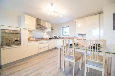 a kitchen with white cabinets and a table and chairs at Luxury Riverview City Centre Apartment in Glasgow