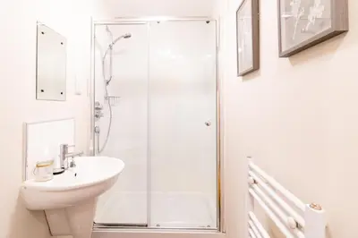 a white bathroom with a shower and a sink at Luxury Riverview City Centre Apartment in Glasgow