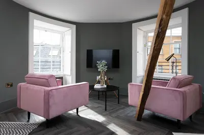 a living room with pink chairs and a tv at 29 Queen Street Aparthotel in Edinburgh