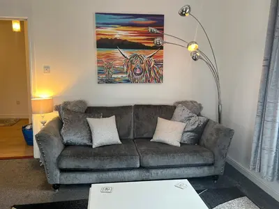 a living room with a couch and a painting at Ayr Cozy Corner Apartment in Ayr