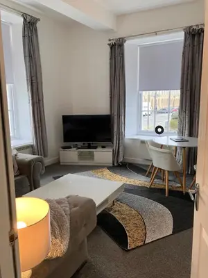 a living room with a couch and a tv at Ayr Cozy Corner Apartment in Ayr
