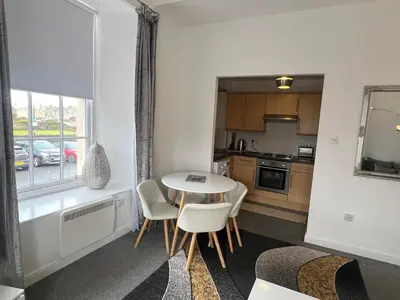 a kitchen with a table and chairs in a room at Ayr Cozy Corner Apartment in Ayr