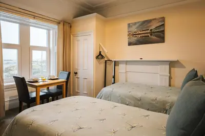 a hotel room with two beds and a desk and a window at Eilidh’s Guest House in Port Ellen