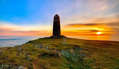 a lighthouse on top of a hill with the sunset at Eilidh’s Guest House in Port Ellen