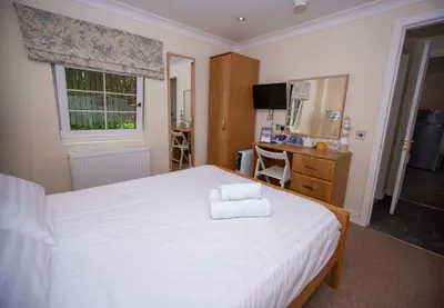 a bedroom with a large white bed and a desk at Braeside Guest House, Loch Lomond in Drymen