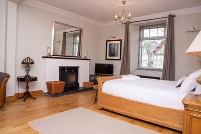 a bedroom with a large bed and a fireplace at Braeside Guest House, Loch Lomond in Drymen