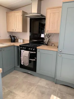 a kitchen with blue cabinets and a black stove at The Roecliffe 54 in Dunoon