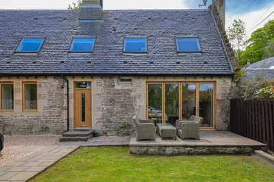 an extension to a stone house with a patio at Fantastic Cottage in Loch Lomond National Park in Alexandria