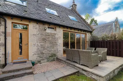 a home with a patio with wicker chairs on it at Fantastic Cottage in Loch Lomond National Park in Alexandria