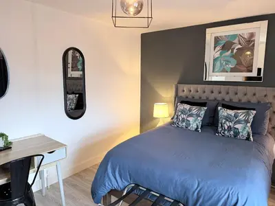a bedroom with a blue bed with a desk and a mirror at No 19 Serviced Apartment in Ayr