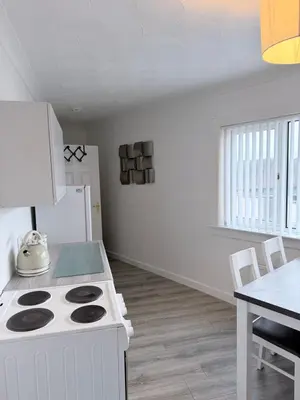 a white kitchen with a stove and a table at No 19 Serviced Apartment in Ayr