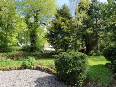 a garden with bushes and trees and a house at Upper Brackendale in Taynuilt