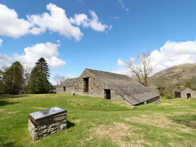 an old stone barn in a field with mountains in the background at Upper Brackendale in Taynuilt