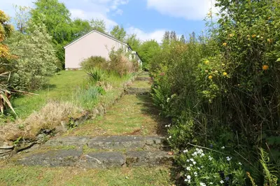 a path in a garden with a building in the background at Innishail in Lochgilphead