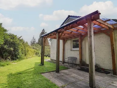 a pergola on the side of a house at Innishail in Lochgilphead