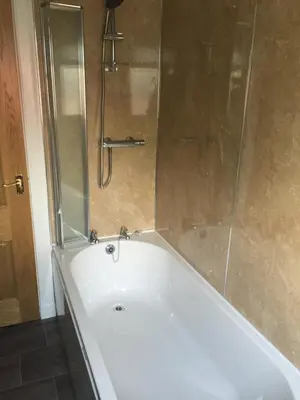 a white bath tub with a glass shower door at Erradill Cottage in Southend