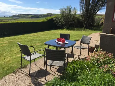 three chairs and a table with a bowl of fruit on it at Erradill Cottage in Southend