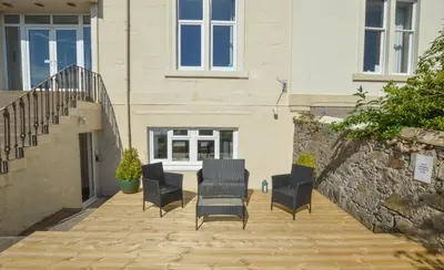 a patio with chairs and a table and a building at No 8 Westbay Apartment in Oban
