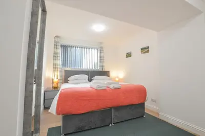 a bedroom with a bed with a red blanket at No 8 Westbay Apartment in Oban