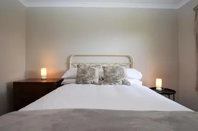 a bedroom with a white bed with two lamps at Nursery Cottage in Kilmun