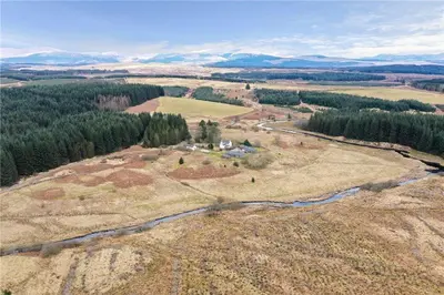 an aerial view of a field with trees and a river at Ochiltree cottage in Newton Stewart