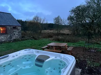 a hot tub in a yard with a picnic table at Ochiltree cottage in Newton Stewart