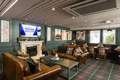 a living room with leather furniture and a television at The Kirkhouse Inn in Strathblane