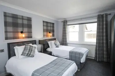 a hotel room with two beds and a window at The Kirkhouse Inn in Strathblane