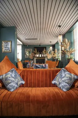 an orange couch with pillows in a living room at The Kirkhouse Inn in Strathblane