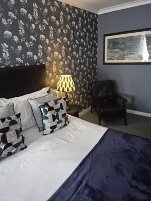 a bedroom with a bed and a chair in a room at The Kirkhouse Inn in Strathblane