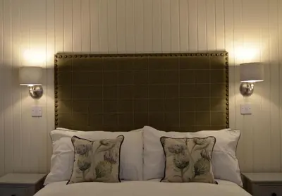 a bed with a green headboard and pillows at Stable Cottage in Arrochar