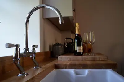 a kitchen sink with a bottle of wine and wine glasses at Stable Cottage in Arrochar
