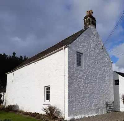 a white building with a chimney on top of it at Stable Cottage in Arrochar