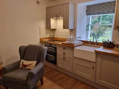 a kitchen with a chair and a sink at Stable Cottage in Arrochar