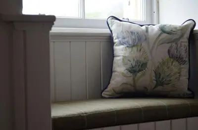 a pillow sitting on a chair in front of a window at Stable Cottage in Arrochar
