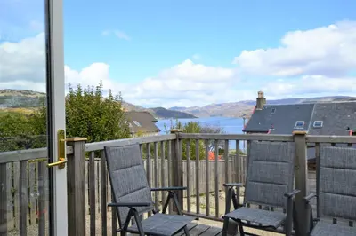 two chairs on a balcony with a view of the water at High Beach Cottage in Kames