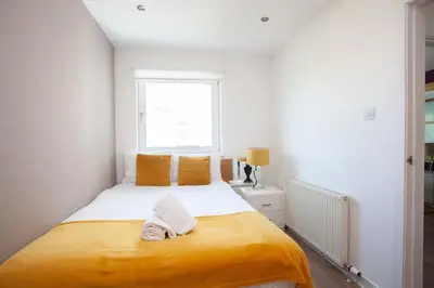 a bedroom with a large yellow bed with a window at Mosspark Boulevard Exec Apartment ii - Free Parking in Glasgow