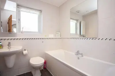 a white bathroom with a toilet and a sink at Mosspark Boulevard Exec Apartment ii - Free Parking in Glasgow