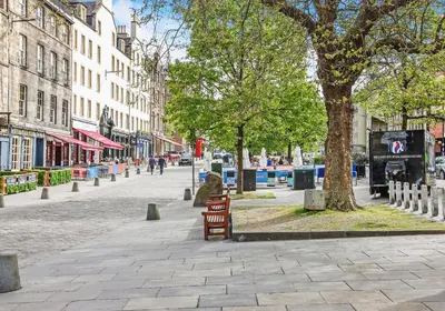 a bench on a city street with a tree and buildings at Argyl - Central Old Town Mews Home with Parking in Edinburgh