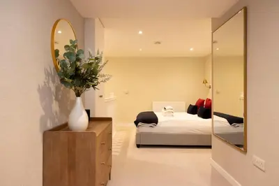 a bedroom with a bed and a mirror and a vase with flowers at Argyl - Central Old Town Mews Home with Parking in Edinburgh