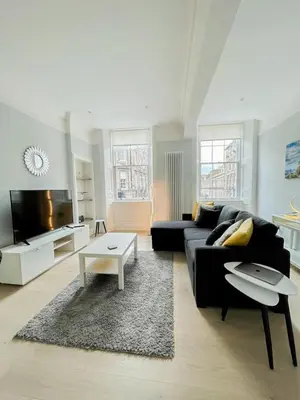 a living room with a black couch and a table at Modern & Spacious 1 Bed Apt, West End in Edinburgh