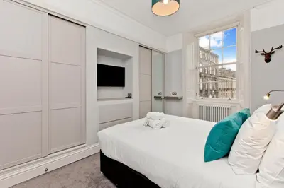 a white bedroom with a bed and a window at Modern & Spacious 1 Bed Apt, West End in Edinburgh