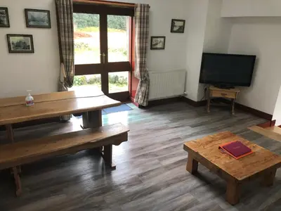 a living room with a table and a television at Merrick Cottage in Bargrennan