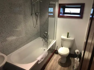 a bathroom with a tub and a toilet and a sink at Merrick Cottage in Bargrennan