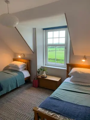 a attic bedroom with two beds and a window at Arran School House - Blackwaterfoot, Isle of Arran in Blackwaterfoot