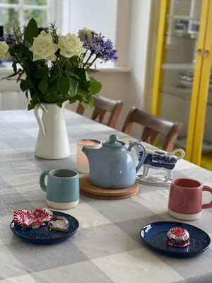 a table with blue plates and a vase with flowers at Arran School House - Blackwaterfoot, Isle of Arran in Blackwaterfoot