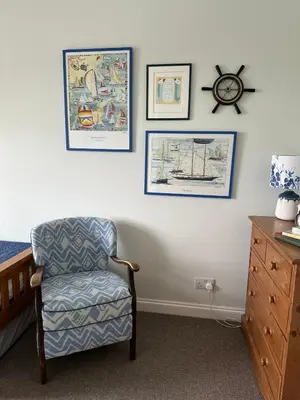a bedroom with a chair and pictures on the wall at Arran School House - Blackwaterfoot, Isle of Arran in Blackwaterfoot