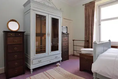 a bedroom with a white cabinet and a dresser at Kimberley Apartment in Dunoon