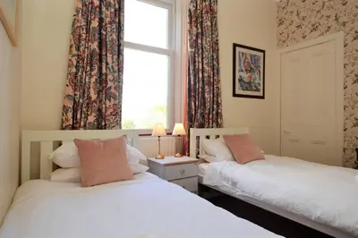 two twin beds in a room with a window at Kimberley Apartment in Dunoon