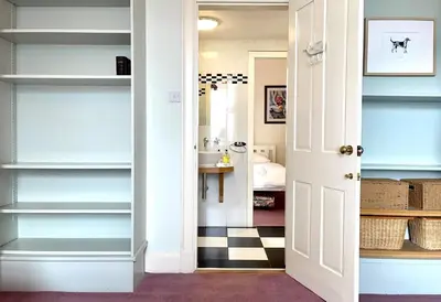 a hallway with white shelves and a room with a bed at Kimberley Apartment in Dunoon